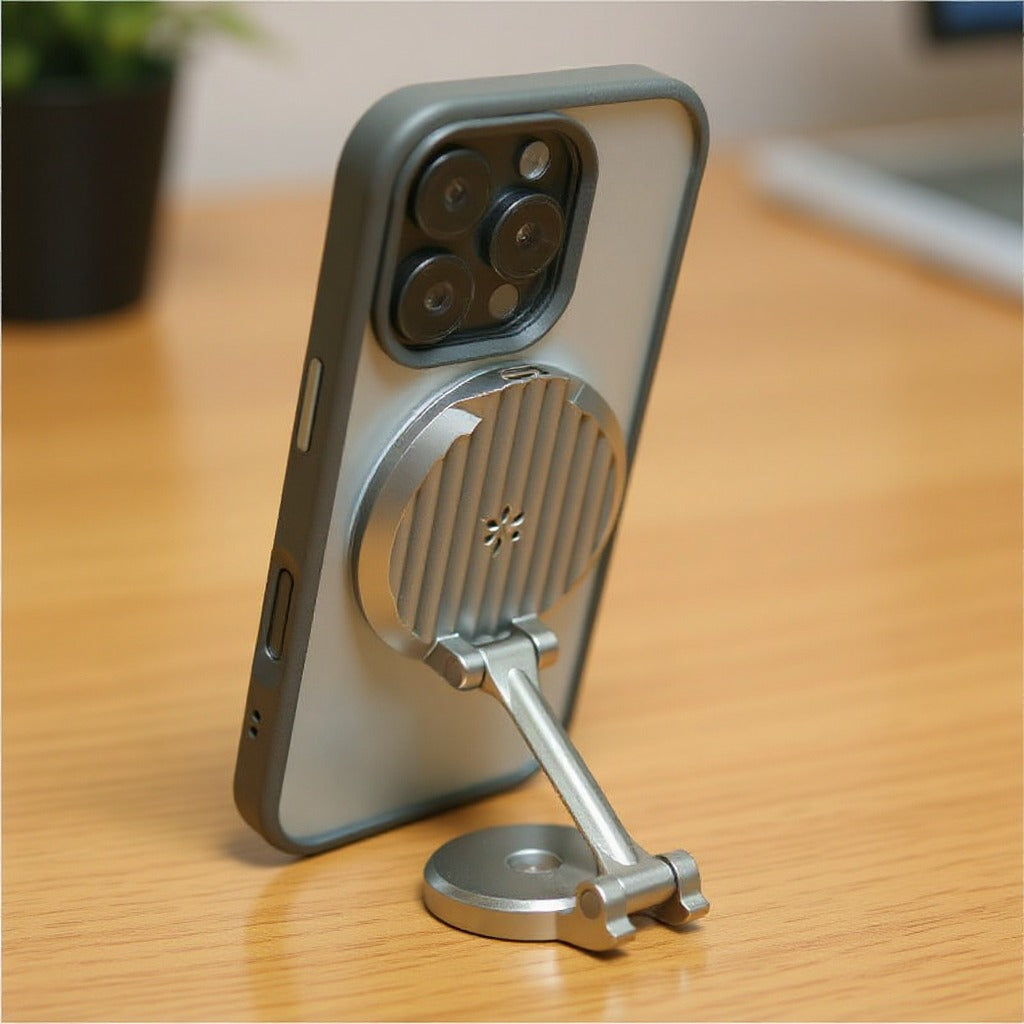A gray protective phone case with a built-in metallic silver magnetic kickstand, shown propped up on a wooden desk.