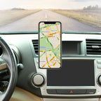 Phone with map app on a car dashboard with a road visible through the windshield