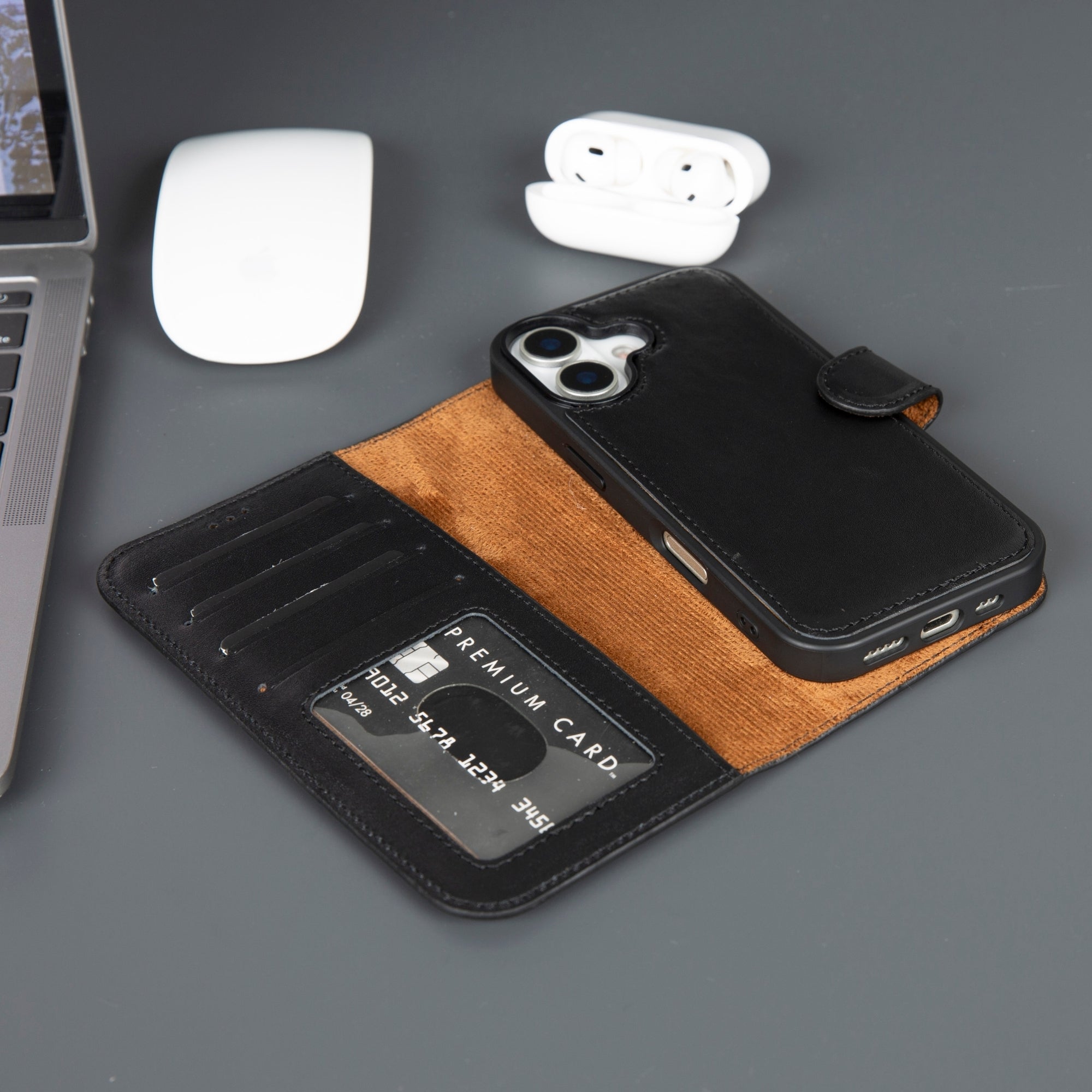 Phone case with card holder on a desk with laptop, mouse, and earbuds.