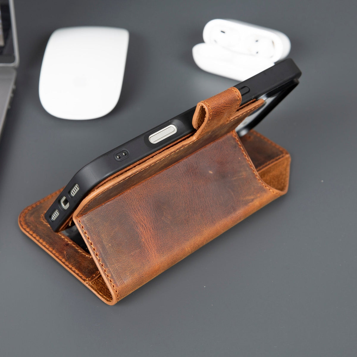 Brown leather phone case with a phone inside on a gray surface